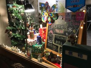 Miaoli Sanyi Travelling Homestay في ساني: نافذة عيد الميلاد مع شجرة عيد الميلاد و لوحة