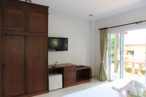 a bedroom with a large wooden cabinet and a television at Shangrilah Bungalow in Mae Nam