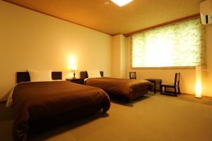 a hotel room with two beds and a window at Hotel Oak Forest in Hakuba