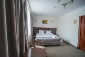 a bedroom with a bed, chair and a lamp at Alma in Almaty