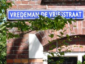 un cartello blu sulla strada sul lato di un edificio di mattoni di Hus a Leeuwarden