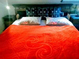 1 cama roja grande con 2 almohadas en Villa Victoria, en Mosonmagyaróvár