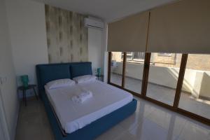 a bedroom with a blue bed with a large window at Valletta Dream Suites Penthouse in Valletta