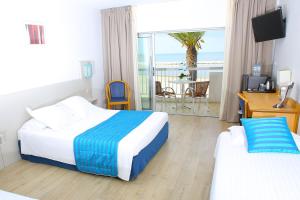 a hotel room with two beds and a balcony at Hôtel Restaurant Splendid Camargue in Le Grau-du-Roi