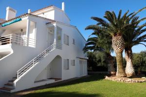 una casa blanca con palmeras en el patio en AMANECER EN PORT D´ADDAIA en Es Mercadal