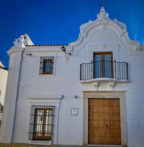 biały budynek z drewnianymi drzwiami i balkonem w obiekcie La Hermandad de Villalba w mieście Villalba de los Barros