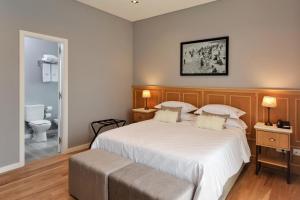 a bedroom with a large white bed and a toilet at Altos de Guemes Hotel in Mar del Plata