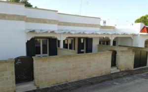 a white building with a brick fence in front of it at Casa Roberto in Campomarino