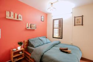 a bed in a room with an orange wall at Kalon Homestay, Hai Bà Trưng, HN in Hanoi