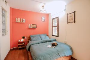 ein Schlafzimmer mit einer orangefarbenen Wand und einem Bett in der Unterkunft Kalon Homestay, Hai Bà Trưng, HN in Hanoi