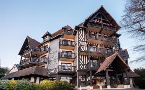 um edifício alto com preto e branco em Best Western Plus Hostellerie Du Vallon em Trouville-sur-Mer