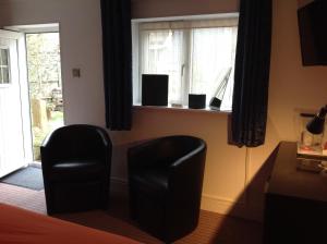 a bedroom with two black chairs and a window at The old post office in Bicester