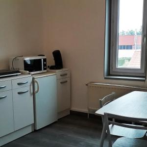 a small kitchen with a table and a microwave at Appart comme chez soi in Pusignan