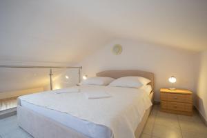 a bedroom with a large white bed and a night stand at Apartment Smuljic in Vrboska