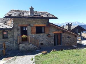 ein Steinhaus mit einer Veranda und einem Balkon in der Unterkunft Casetta di montagna Viuex in La Magdeleine