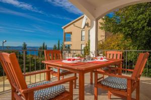 - une table et des chaises en bois sur une terrasse avec vue sur l'océan dans l'établissement Apartments Maris, à Crikvenica