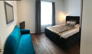 een slaapkamer met een bed en een blauwe bank bij Brig City Garden Apartment in Brig