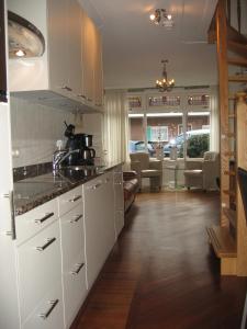 a kitchen with white cabinets and a living room at De Oosterberg in Egmond aan Zee