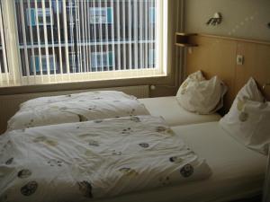 a bed with a white comforter and a window at De Oosterberg in Egmond aan Zee