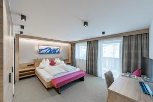 Habitación de hotel con cama grande y escritorio. en Frühstückspension Broser en Obergurgl