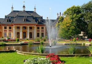 a large building with a fountain in front of a pond at Restaurant und Pension Zur Puppenstube in Stolpen