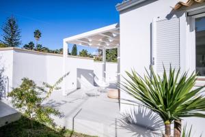 a white house with a patio with a chair at Total White Villa in Fontane Bianche