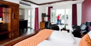 a bedroom with a bed and a living room at Riverside Hotel in Nordhorn