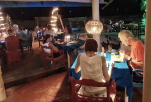 un grupo de personas sentadas en una mesa en un restaurante en Neela's Beach Inn en Hikkaduwa