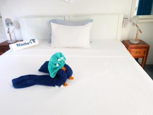 un animal de peluche está sentado en una cama en Neela's Beach Inn, en Hikkaduwa
