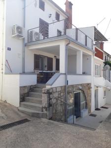 a white house with stairs and a balcony at apartman Lucija in Punat