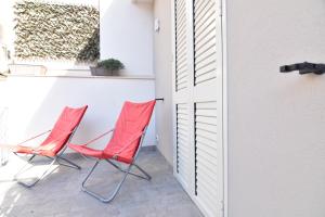 two red chairs sitting on a porch next to a door at The three diamonds of Marina di Ragusa in Marina di Ragusa
