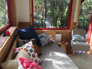 a room with a couch with pillows and a chair at Almabosque Cabañas in Puerto Varas