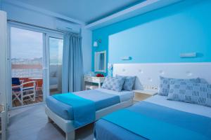 a blue bedroom with two beds and a balcony at Kastro Beach Apartments in Malia