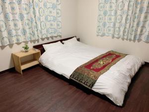 Un pequeño dormitorio con una cama con sábanas blancas y una mesa. en Tokyo Kamakura House en Tokio