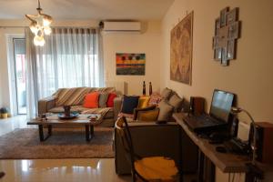 a living room with a couch and a table with a laptop at Georgina's cozy apartment -Metropolitan Hospital- in Piraeus