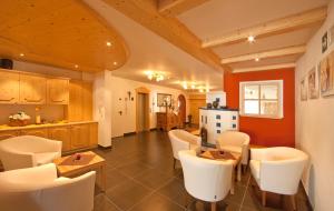 a living room with white chairs and a kitchen at Hotel Waldheim in Valle Di Casies