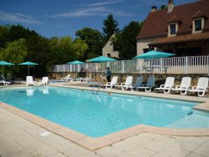 une grande piscine avec des chaises et des parasols dans l'établissement Les Chalets d'Argentouleau, à Sarlat-la-Canéda