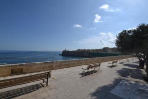 a row of benches on a sidewalk near the water at Valletta Dream Suites Penthouse in Valletta