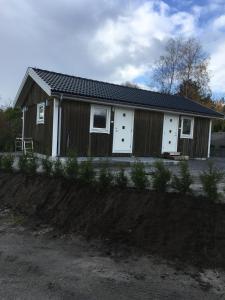 uma pequena casa com portas brancas numa estrada de terra em Långesjö lillstuga em Fjällbacka