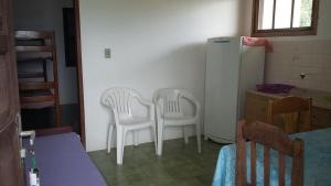 2 sillas blancas en una cocina con nevera en Apartamento do Norte na Ferrugem, en Garopaba