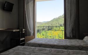 a room with two beds and a window with a view at Hôtel Des Rochers in Marvejols