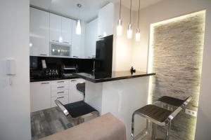 a kitchen with white cabinets and a counter with stools at Diva Lux Apartman in Belgrade