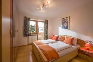 1 dormitorio con 1 cama con almohadas de color naranja y ventana en Appartement Steinbock, en Sankt Johann in Tirol