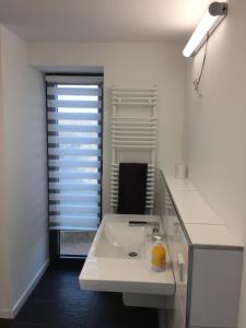 een witte badkamer met een wastafel en een spiegel bij Nummer Zwo in Helgoland