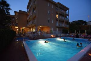 un grupo de personas nadando en una piscina por la noche en Residence Orchidea en Pietra Ligure