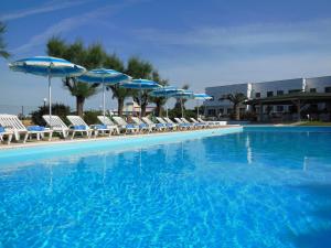 a large swimming pool with chairs and umbrellas at Residence Club Barbara in Ostuni