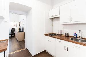 Private Apartment Centertown في بودابست: مطبخ أبيض مع دواليب بيضاء ومغسلة