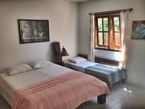 a bedroom with two beds and a window at Village Mata Encantada in Santo André