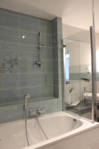 a bathroom with a tub with a shower and a mirror at Weber Apartments in Dresden