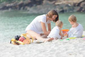 a woman and two children sitting on the beach at Ao Cho Grandview Hideaway Resort in Ko Samed